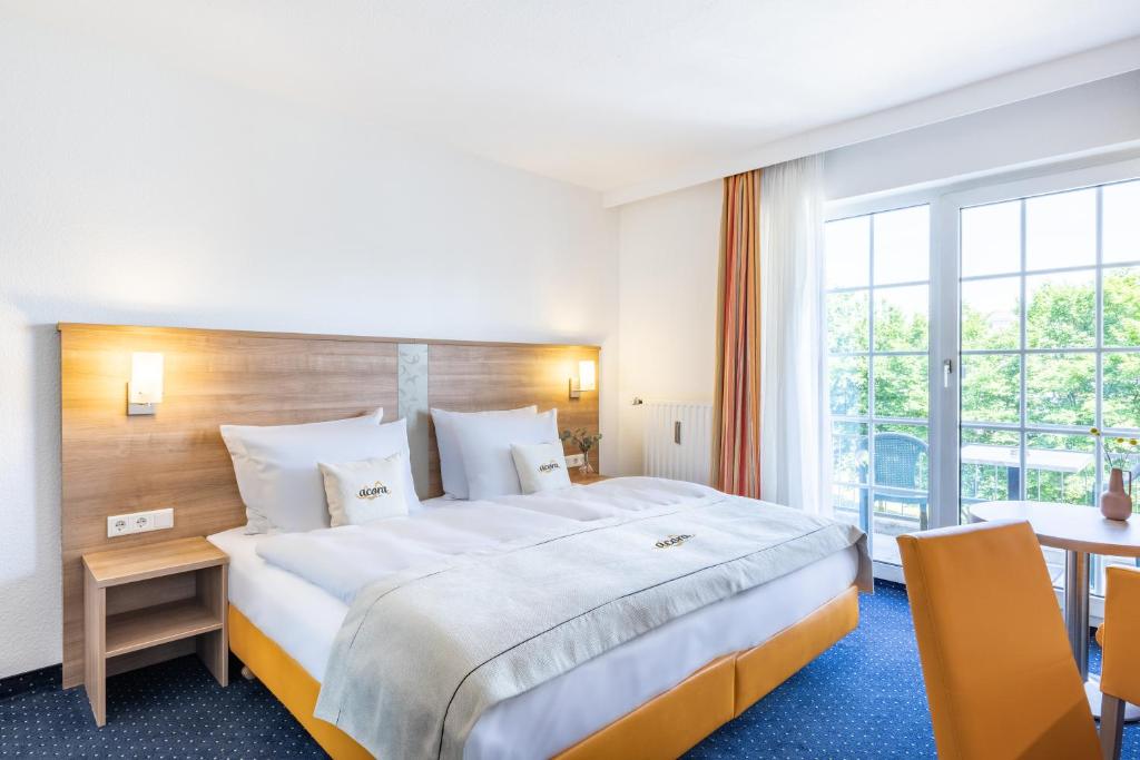 ein Hotelzimmer mit einem großen Bett und einem Tisch in der Unterkunft acora Düsseldorf Living the City in Düsseldorf