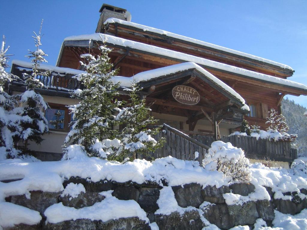 una cabaña de madera con nieve en la parte delantera en Chalet Philibert, en Morzine