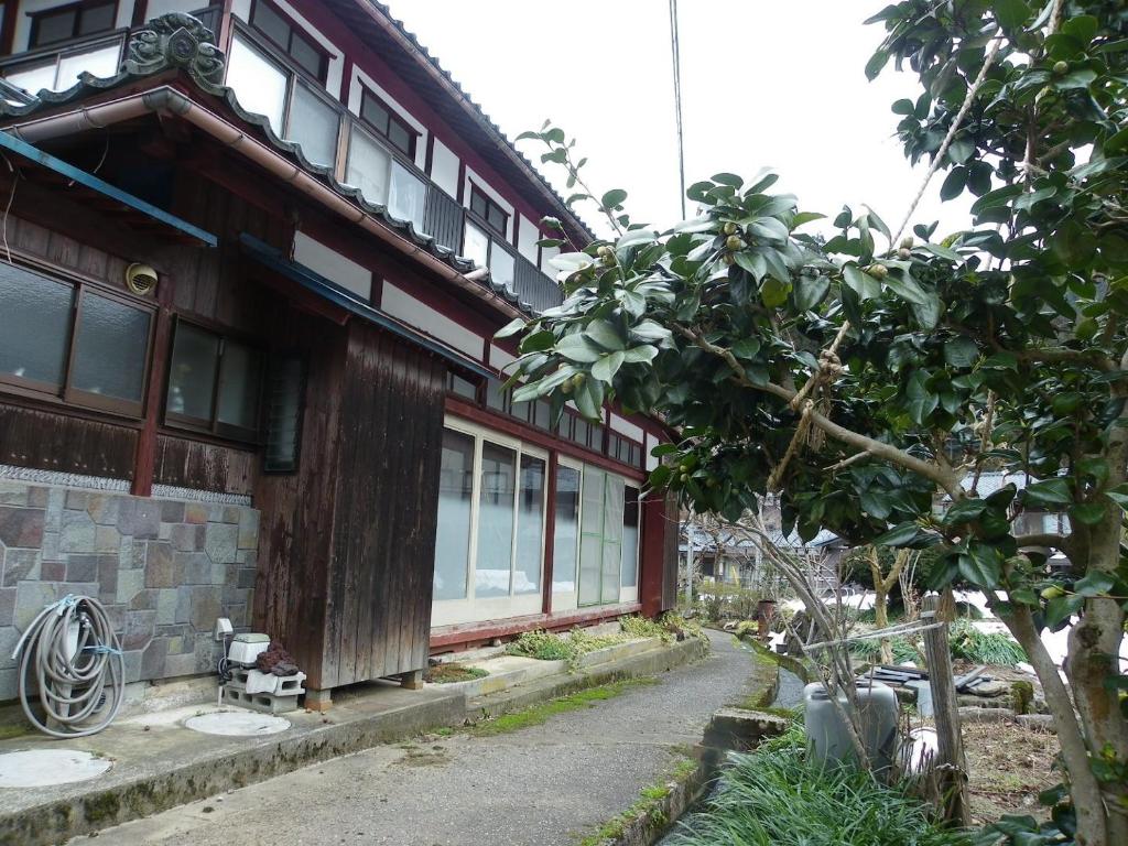 un edificio con un árbol delante de él en Noukaminsyuku Zakuro no Yado / Vacation STAY 15439 en Sabae