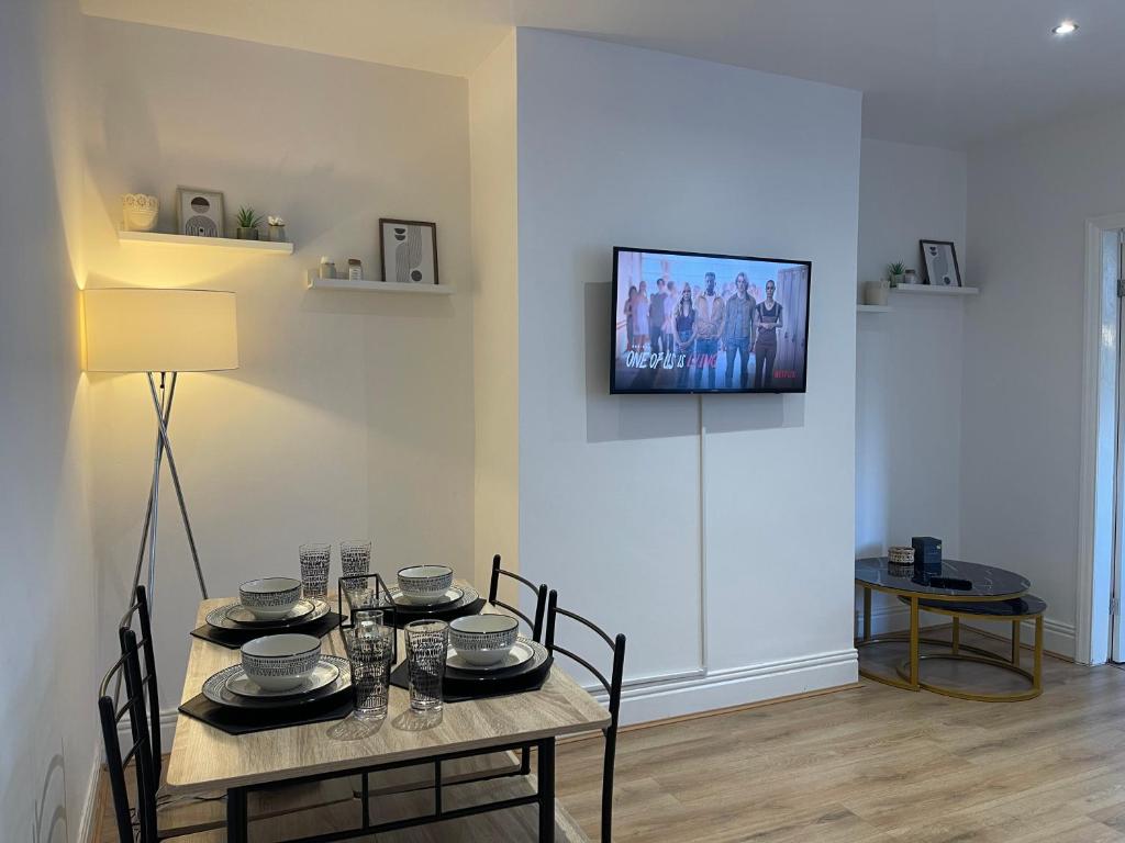 a dining room with a table and a television on the wall at Stylish and Modern 3 bed Apartment with FREE PARKING, in Newcastle upon Tyne