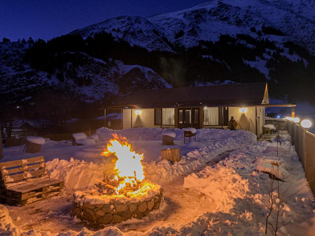 a fire pit in the snow in front of a house at Januka Garden at Sno in Stepantsminda