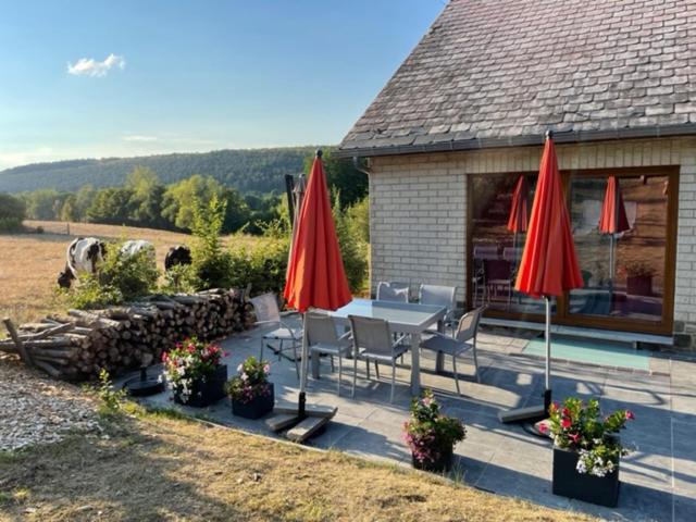 un patio con una mesa y sombrillas rojas en Le gîte de la Champagne, en Olloy-sur-Viroin