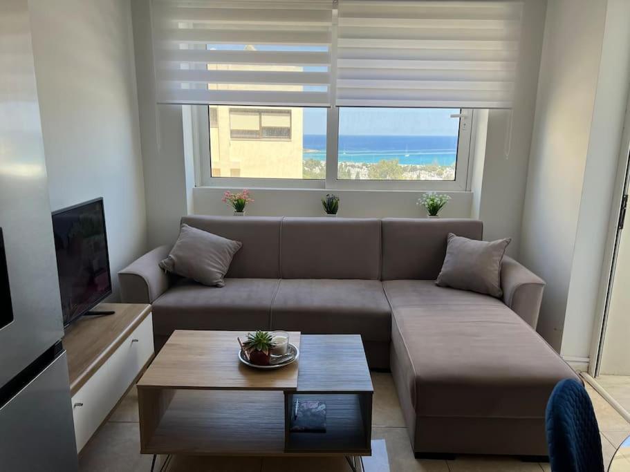 un soggiorno con un divano, un tavolo e una finestra di Karakonero view apartment a Città di Rodi