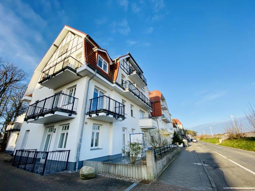 a large white building with balconies on a street at Strandsicht, direkt am Strand in Warnemünde
