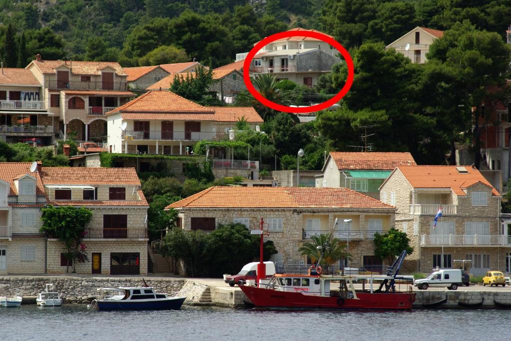 un bote rojo en el agua junto a algunas casas en Apartments by the sea Brna, Korcula - 4333 en Brna