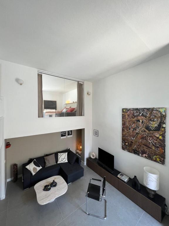 - un salon avec un canapé noir et un miroir dans l'établissement Duplex le Saint Paul, à Arles