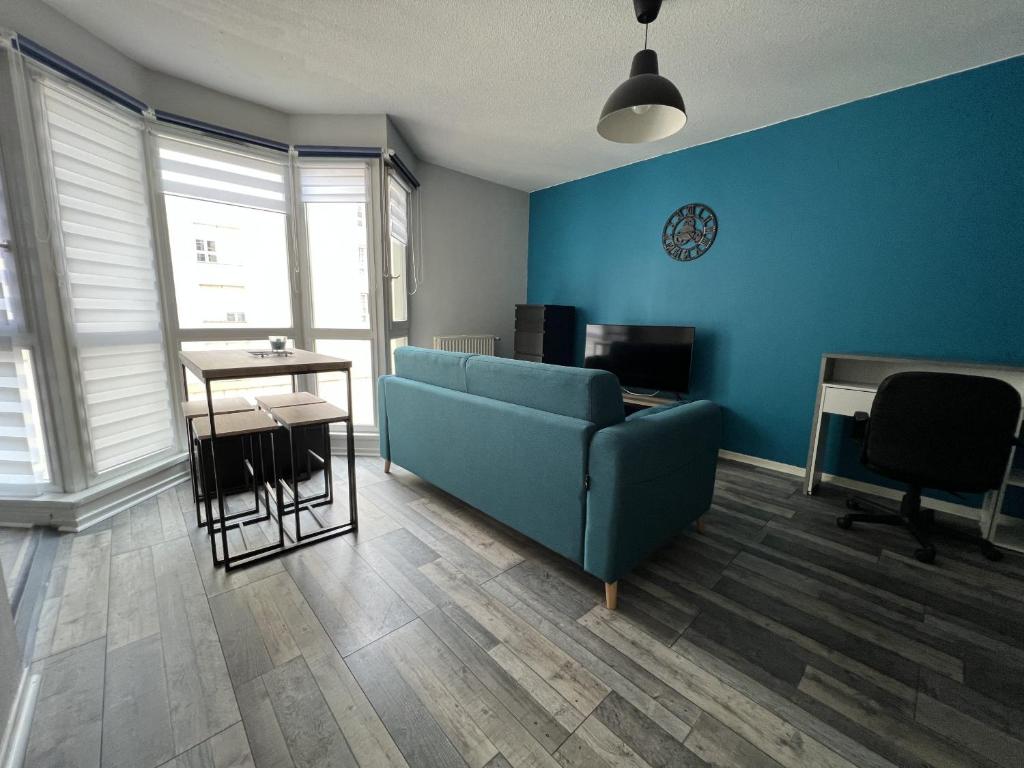 uma sala de estar com um sofá azul e uma mesa em Piscine olympique - Premiere conciergerie em Montpellier