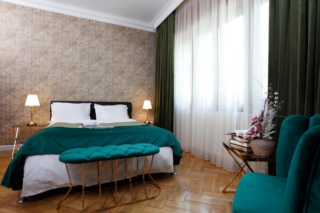 - une chambre avec un grand lit et une couverture verte dans l'établissement Grand Phillip Cismigiu Park Downtown Bucharest, à Bucarest