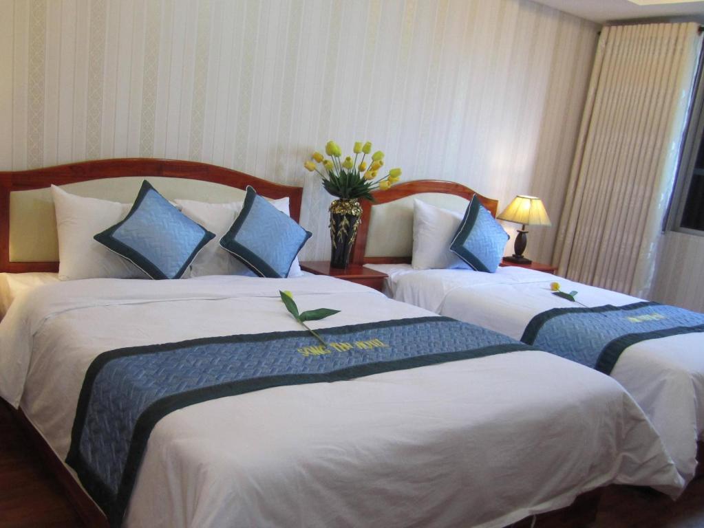 a hotel room with two beds and a vase of flowers at Song Thu hotel in Danang