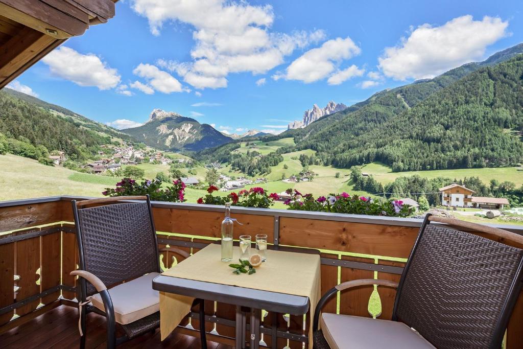 een tafel en stoelen op een balkon met uitzicht op de bergen bij Bergblick App Fichte in Villnoss