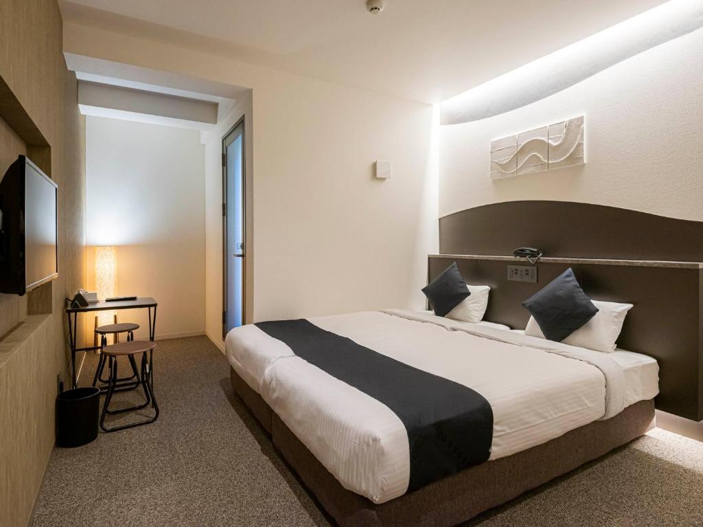ein Hotelzimmer mit einem großen Bett und einem TV in der Unterkunft Seiei Hotel Kyoto Kawaramachi in Kyoto
