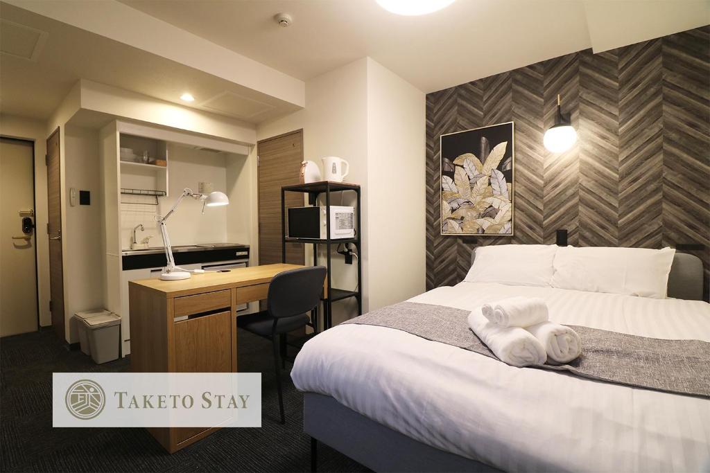 Pokój hotelowy z łóżkiem i biurkiem w obiekcie TAKETO STAY PREMIERE SAPPORO Eki w mieście Sapporo