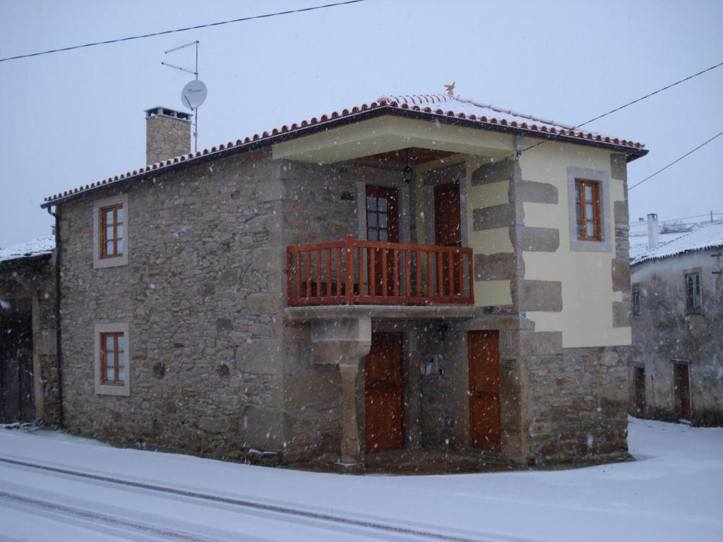 een stenen gebouw met een balkon in de sneeuw bij Casa do Planalto Mirandês in Miranda do Douro