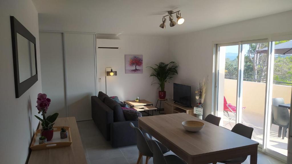 ein Wohnzimmer mit einem Tisch und einem Sofa in der Unterkunft Les Bosquets JOLY in Montauroux