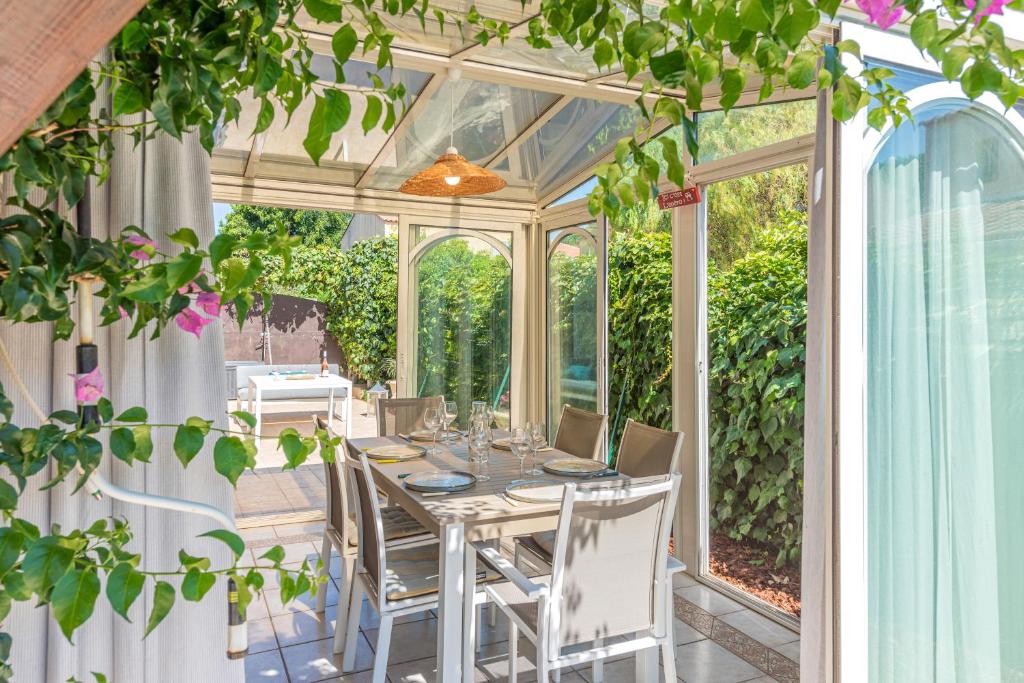 a conservatory dining room with a table and chairs at MAISON COSY avec petite piscine in Six-Fours-les-Plages