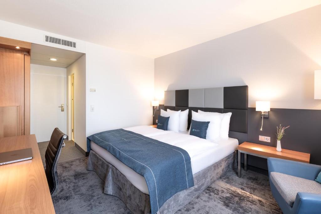 una camera d'albergo con un grande letto con una coperta blu di Select Hotel Rüsselsheim a Rüsselsheim