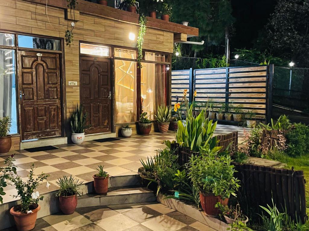 eine Terrasse mit Topfpflanzen und einer Holztür in der Unterkunft House of lights in Solan