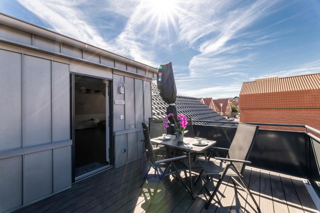 einen Balkon mit einem Tisch und Stühlen auf dem Dach in der Unterkunft Sommerwind Borkum Alfonso Wohnung 3 - Urlaub mit Hund in Borkum