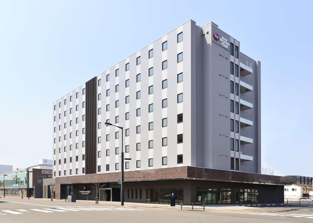 een groot wit gebouw op een straat met een straatlicht bij Best Western Plus Hotel Fino Chitose in Chitose