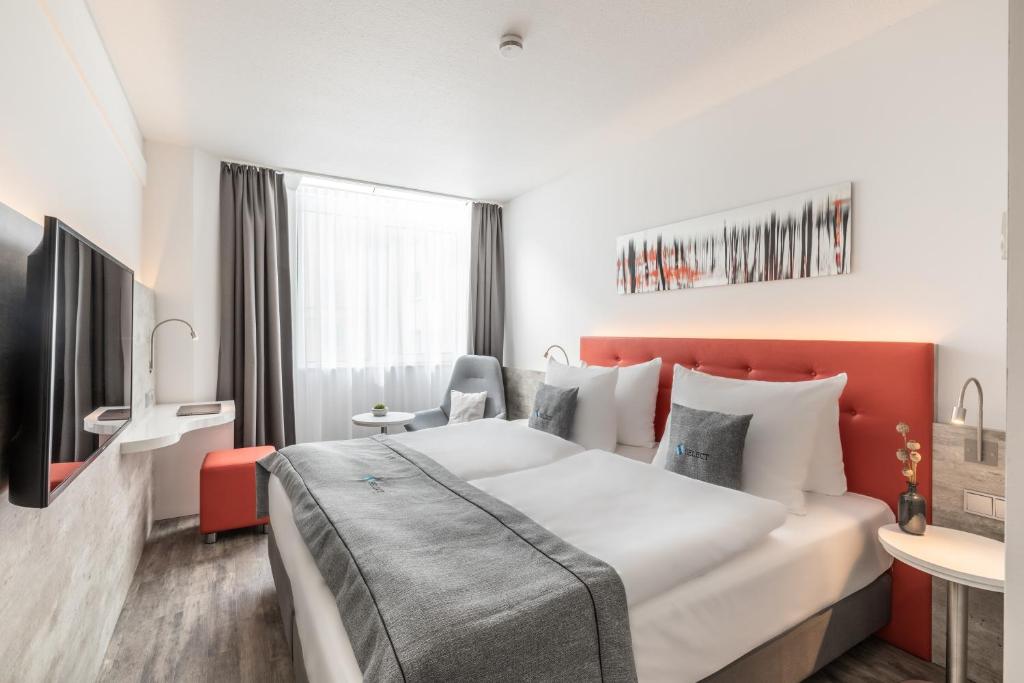 ein Hotelzimmer mit einem großen Bett und einem Schreibtisch in der Unterkunft Select Hotel Wiesbaden City in Wiesbaden