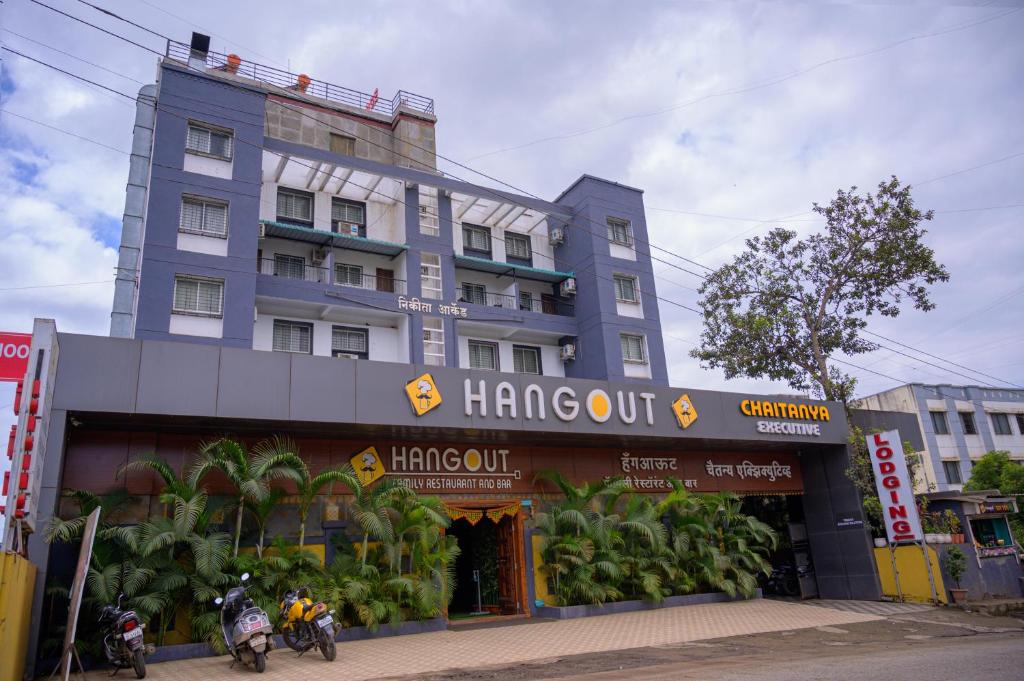 a large blue building with people on motorcycles in front of it at Hotel Hangout in Pune