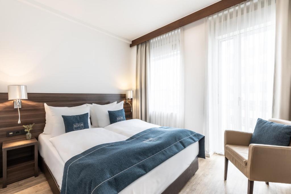 a bedroom with a large bed and a chair at Novum Hotel Continental Frankfurt in Frankfurt