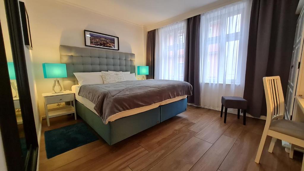 a bedroom with a bed and two windows and a chair at Hotel Domizil in Erfurt