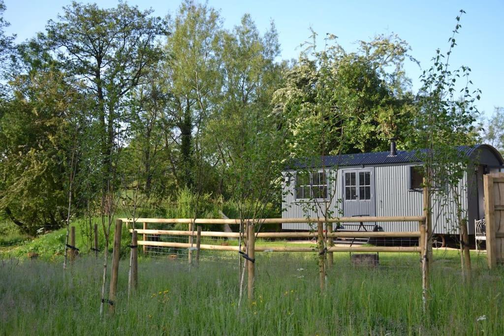 a cabin in the middle of a field with a fence at Large Luxury Shepherds Hut with Hot Tub nr Bath in Bristol