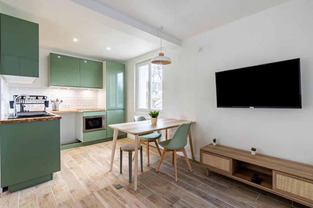 una cocina con armarios verdes, mesa y sillas en Welcome perche ! Appartements 3 étoiles à NOGENT le Rotrou en Nogent-le-Rotrou