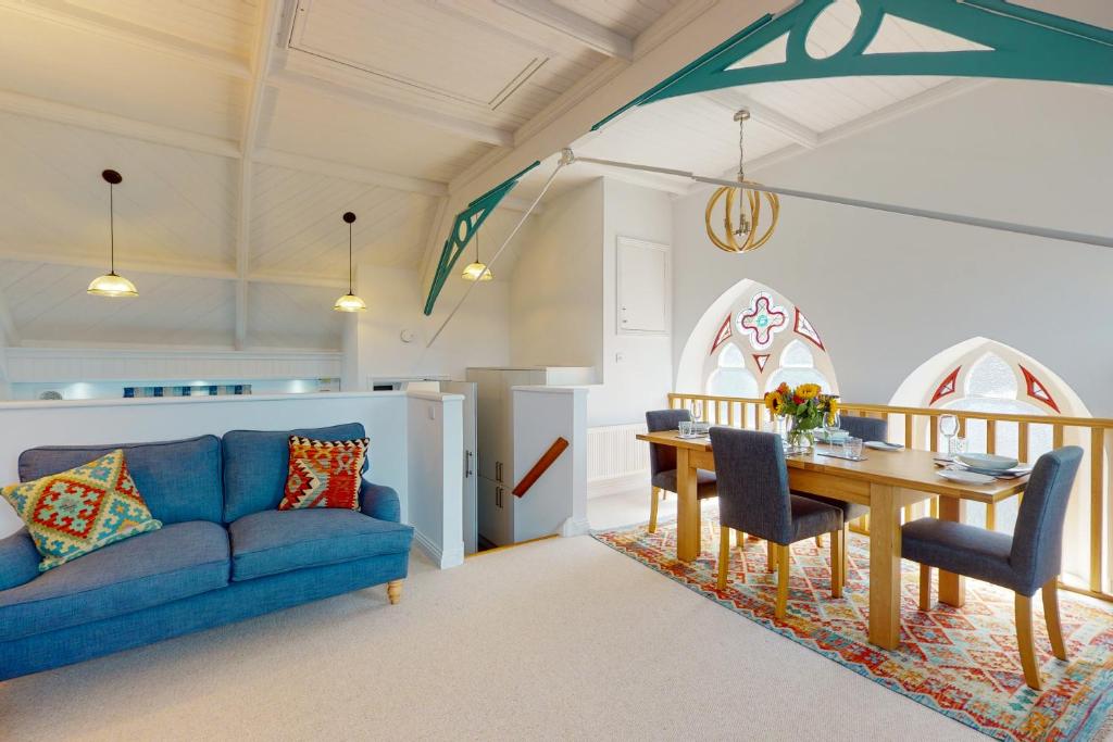 a living room with a blue couch and a table at Church Mews in Exmouth