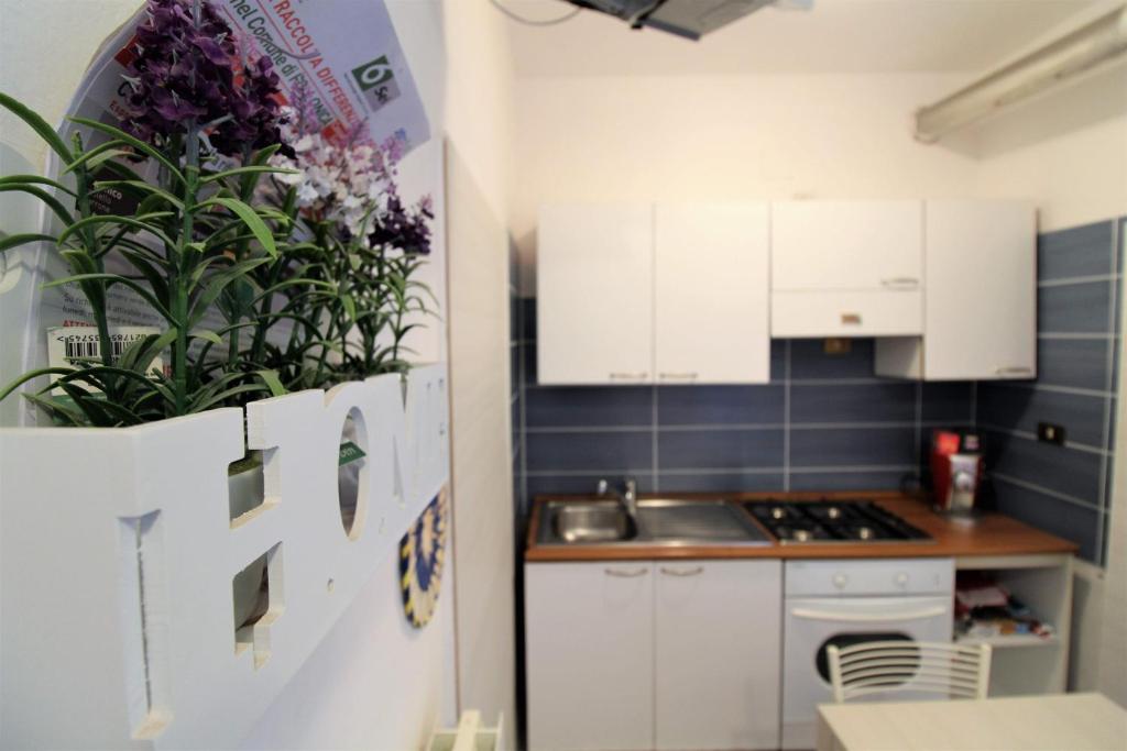 uma cozinha com armários brancos e flores roxas no frigorífico em Casa Francia em Follonica