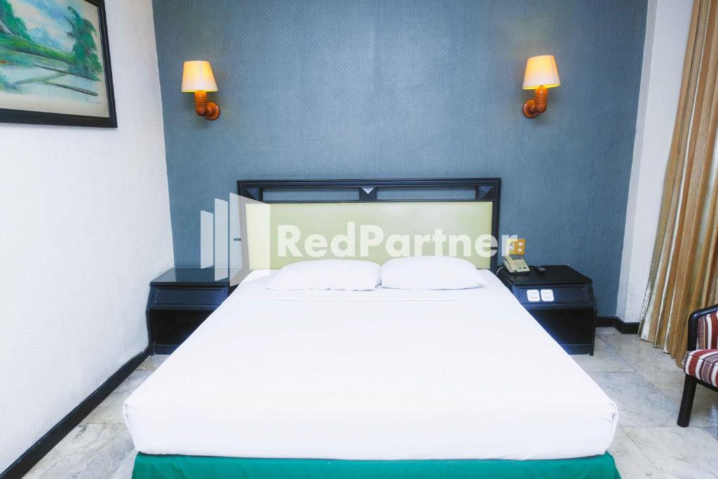 een slaapkamer met een wit bed in een blauwe muur bij Hotel Yasmin Makassar Mitra RedDoorz in Makassar