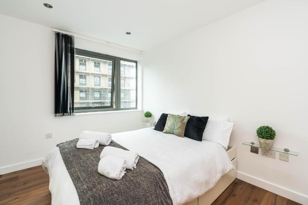 a white bedroom with a large bed and a window at Lovely one bedroom apartment in Greater London, ID required in London