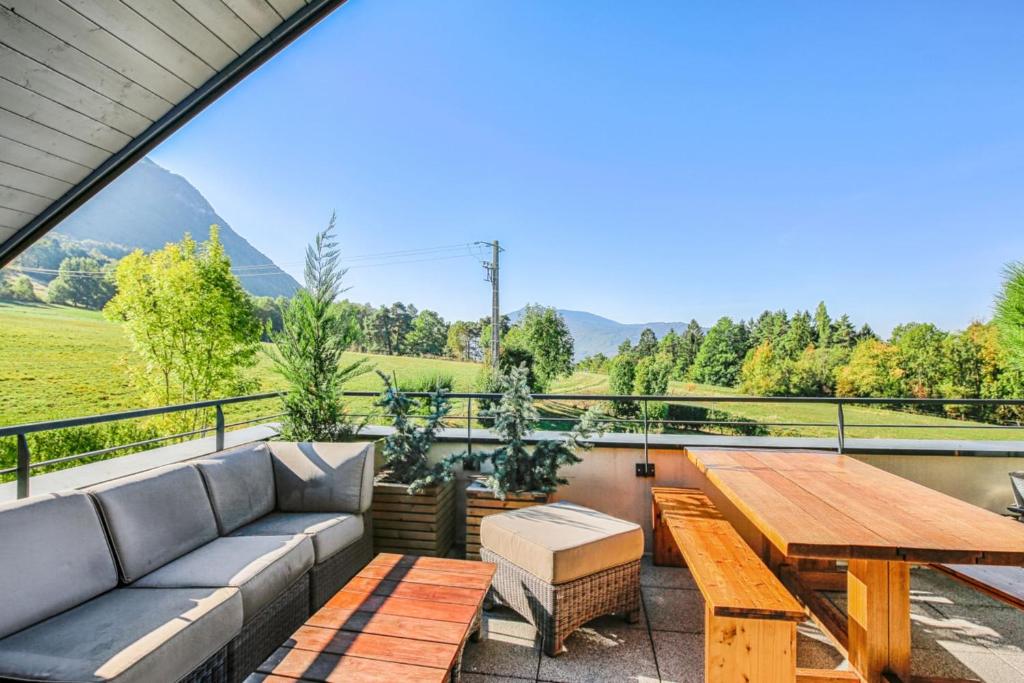 d'une terrasse avec un canapé et une table en bois. dans l'établissement Panorama du Bellay - Welkeys, à Annecy-le-Vieux