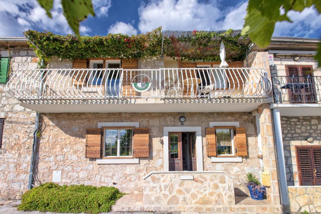 ein Steinhaus mit einem Balkon und einem Hund darauf in der Unterkunft Villa Cincilograd in Jelsa