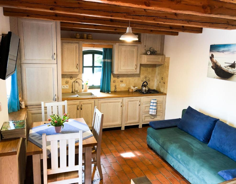 a kitchen and a living room with a couch and a table at Czerwony domek nad samym jeziorem in Mikołajki