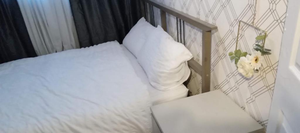 un letto con lenzuola e cuscini bianchi in una stanza di Lovely 1 bedroom flat 5 minutes walk from station a Londra