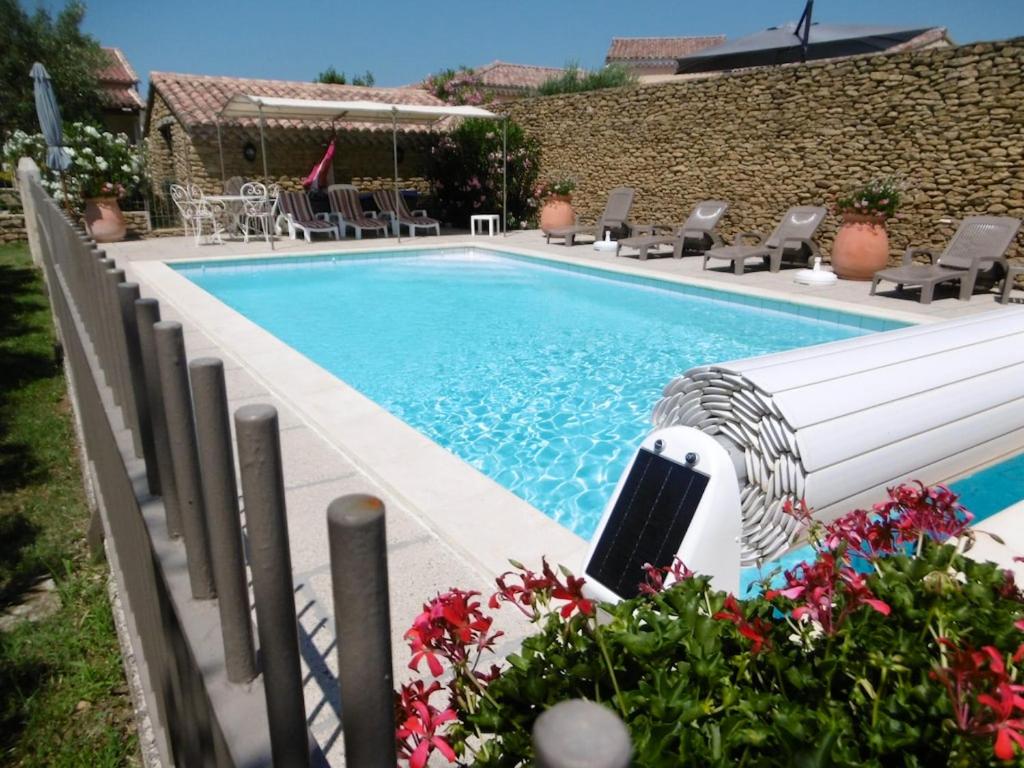a swimming pool in a yard with chairs and flowers at Villa de 2 chambres avec piscine partagee jardin clos et wifi a Grillon in Grillon