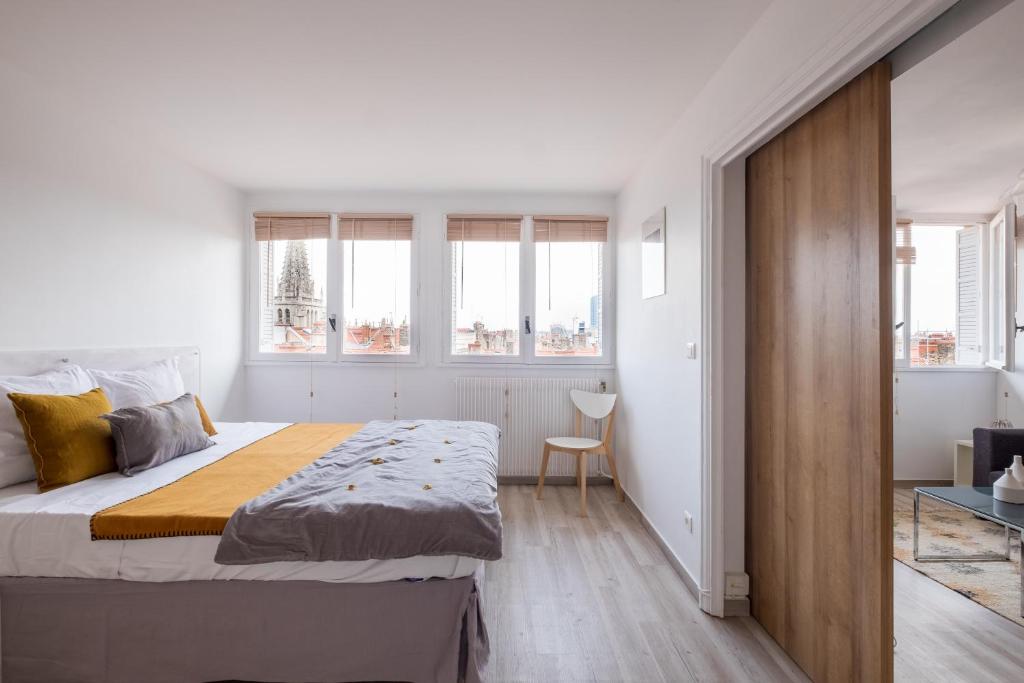 una camera bianca con un grande letto e finestre di HONORÊ SUITE SAINT ANTOINE a Lione