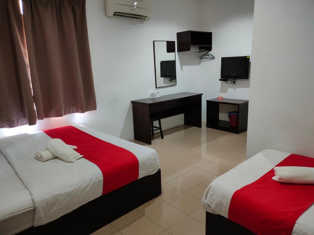Habitación de hotel con 2 camas, escritorio y TV. en Hotel Star Inn, en Teluk Intan