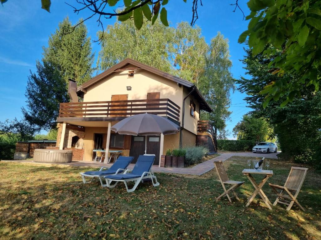 een huis met 2 ligstoelen en een parasol bij Holiday Home Vito in Stubička Slatina