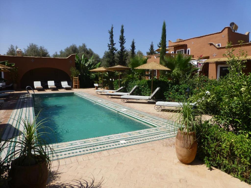 a swimming pool with chairs and umbrellas next to a house at Palais Mandarine in Taroudant