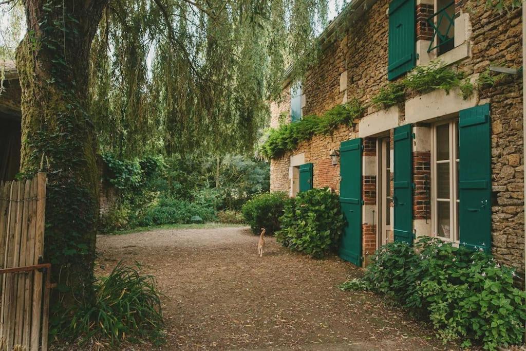 a building with green doors and a tree next to it at Cocon cosy et déconnecté 30min Puy du Fou - 2 chambres et 1 canapé lit in Bazoges-en-Pareds
