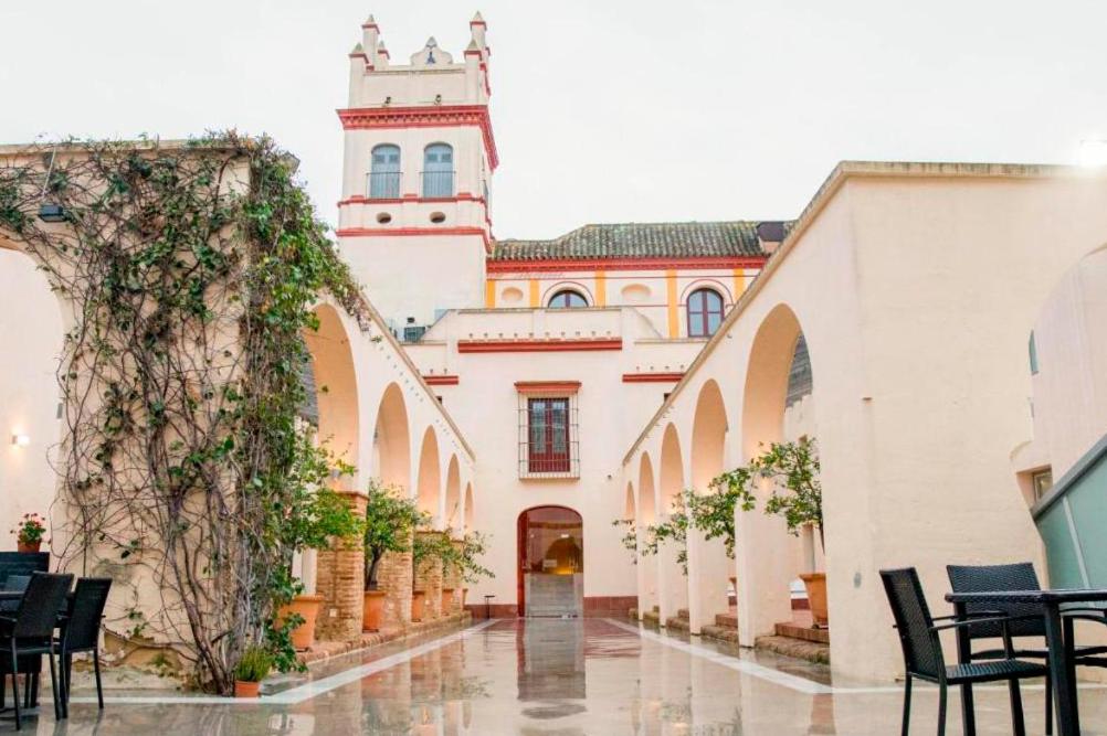 un patio de un edificio con una torre de reloj en Hotel Palacio Marqués de Arizón en Sanlúcar de Barrameda