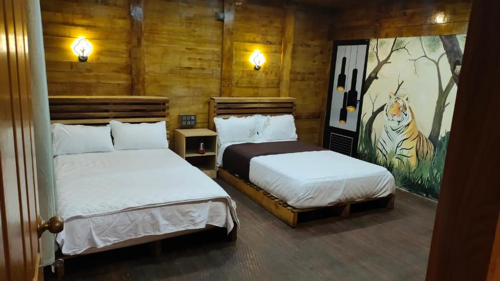 a bedroom with two beds and a painting on the wall at Mountainmist wooden cottages in Ramakkalmedu