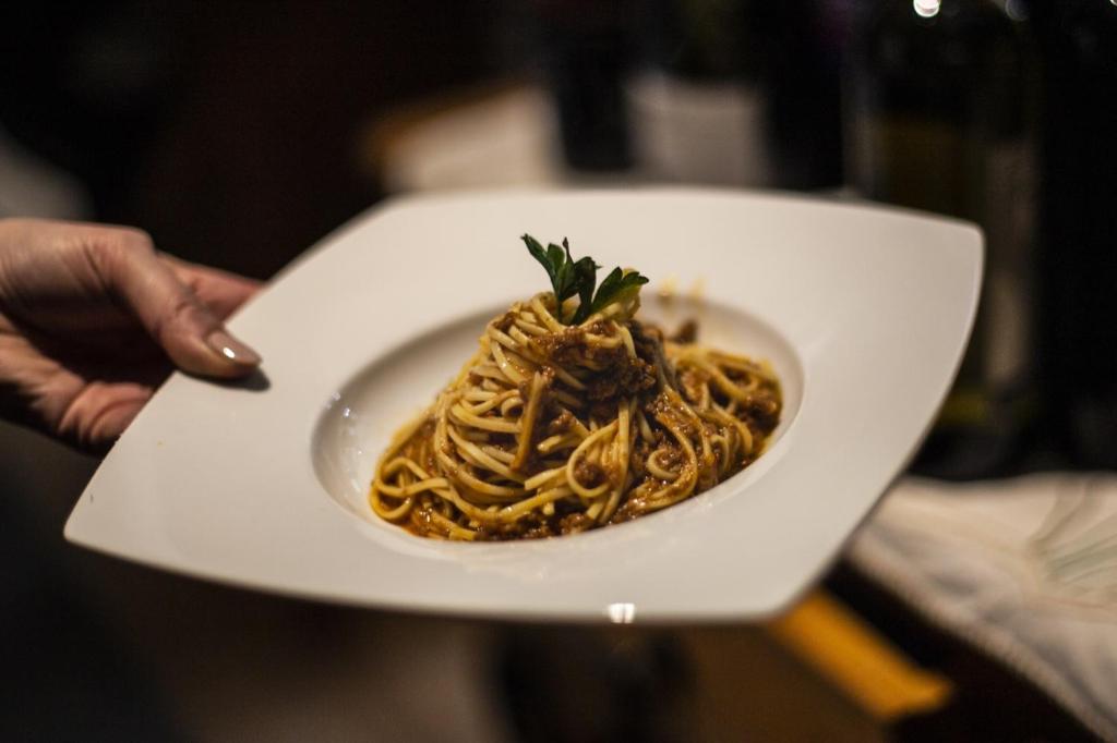 a person holding a white plate of spaghetti at Hotel Edelweiss in Limone Piemonte