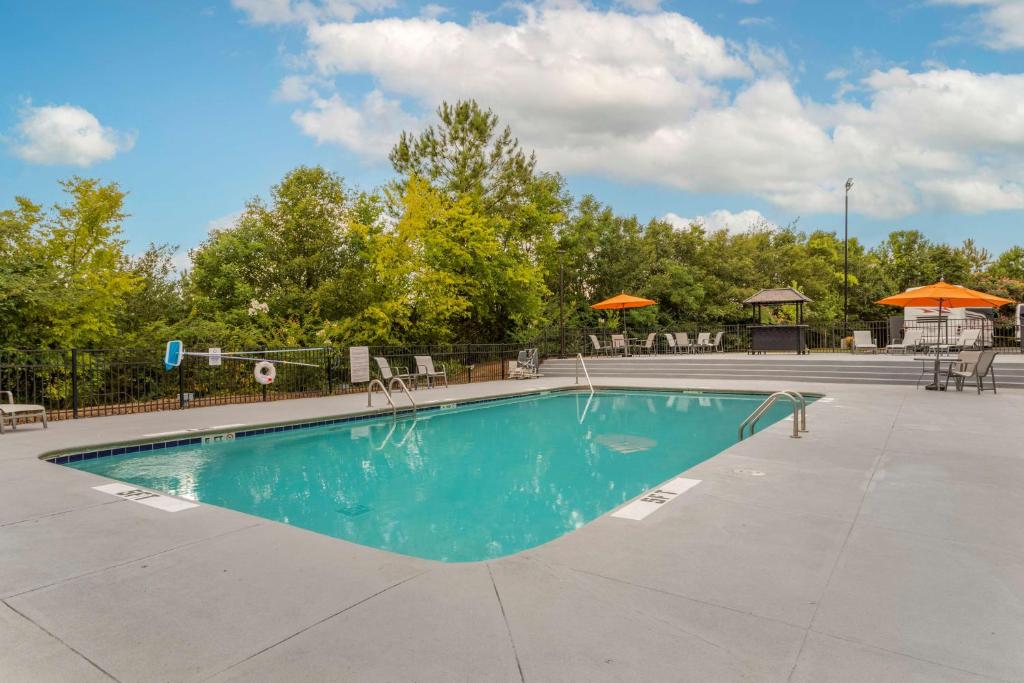 a swimming pool at a resort with trees and umbrellas at Best Western Plus Magnolia Inn & Suites in Cleveland