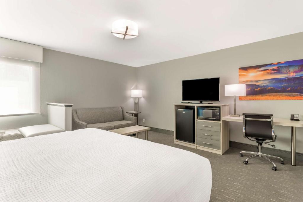 a hotel room with a bed and a flat screen tv at Best Western Plus Magnolia Inn & Suites in Cleveland