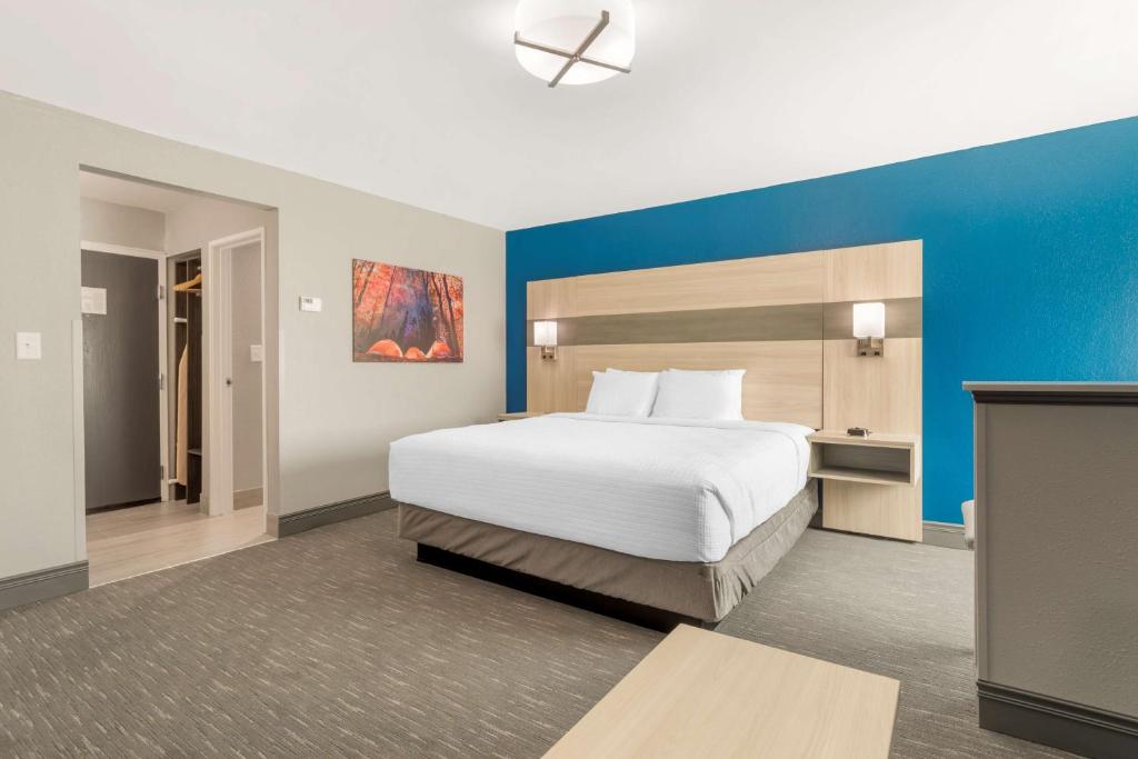 a bedroom with a large bed with a blue wall at Best Western Plus Magnolia Inn & Suites in Cleveland