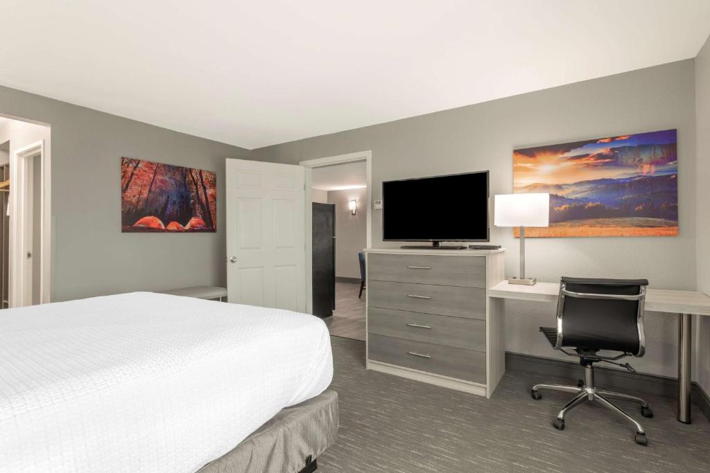 a hotel room with a bed and a desk with a television at Best Western Plus Magnolia Inn & Suites in Cleveland